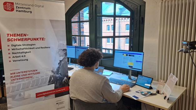 Station Design im KI-Showroom: Person sitzt am Computer der Arbeitsstation.