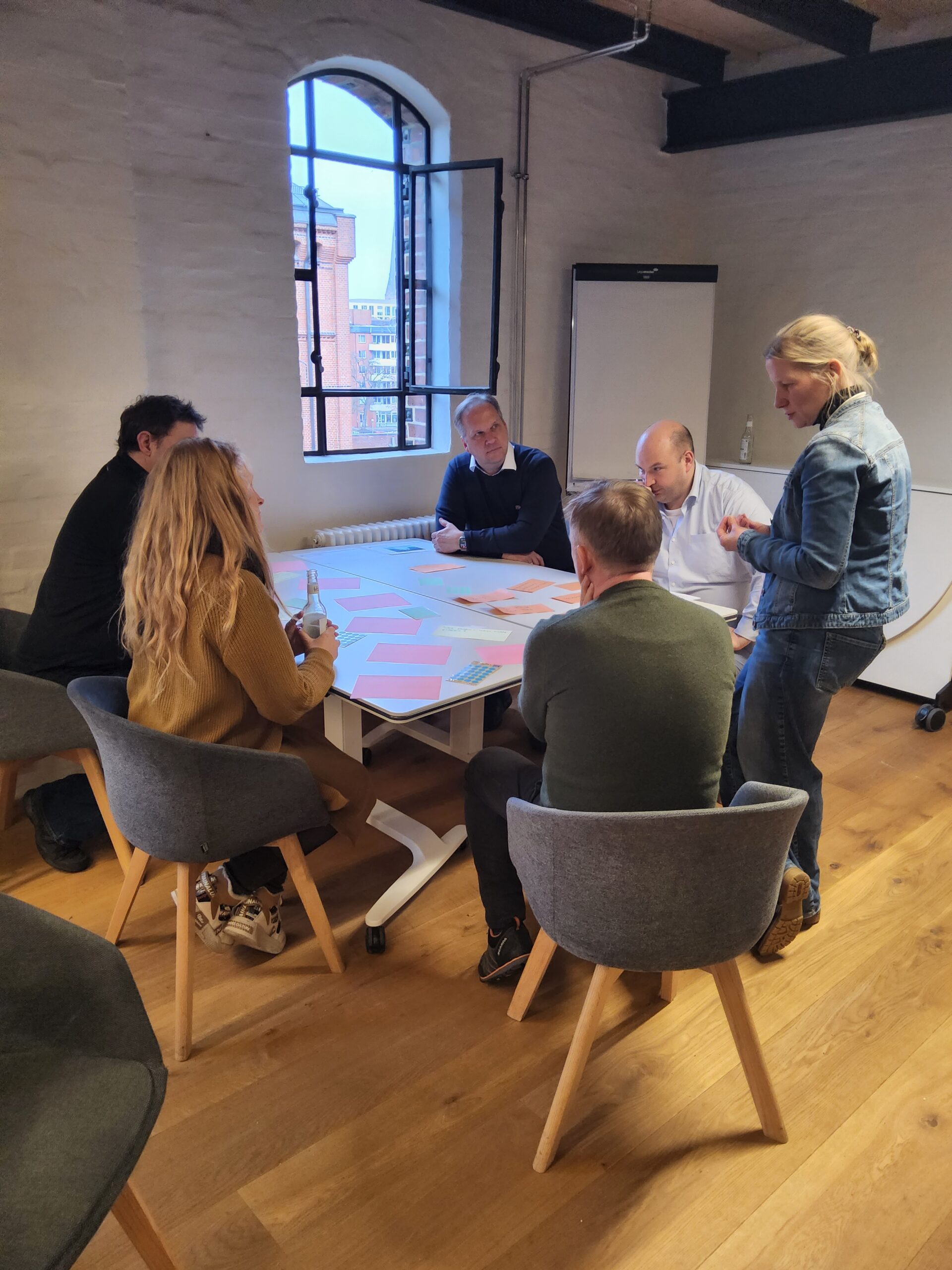 mehrere Menschen sitzen an einem Tisch und besprechen Abläufe